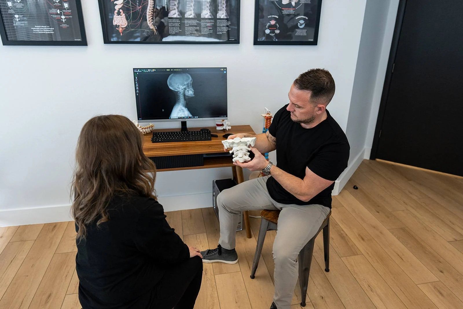 A MŪV chiropractor talking a patient through her X-ray in the exam room